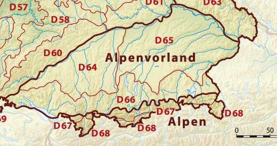 Blick über einen Bergsee auf bewaldete Hänge und die Alpenkette; am Hang ein Schloss über einem Ort