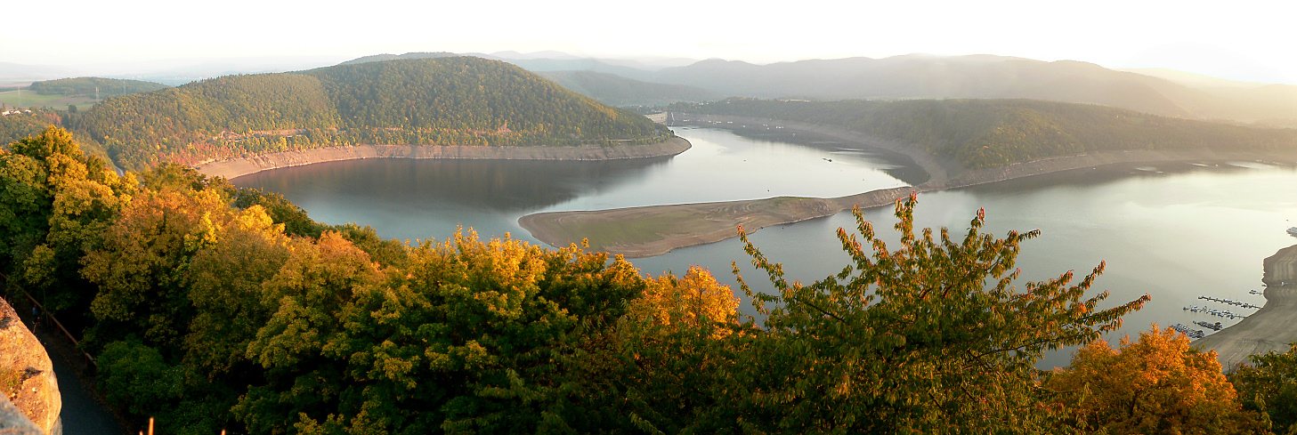 Der Edersee von oben: der Stausee zieht sich in Windungen durch herbstlich gefärbte Waldhänge.
