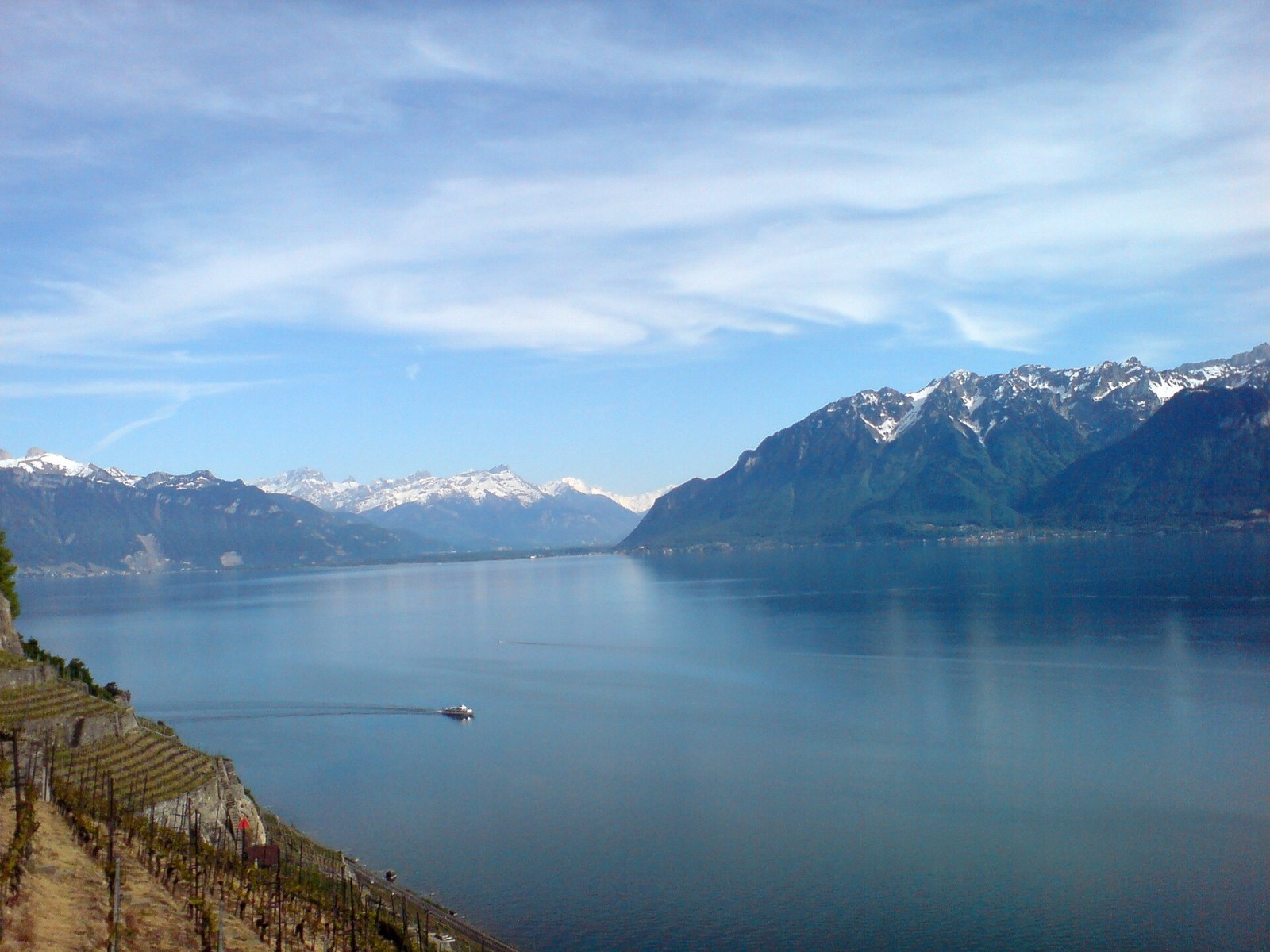 Weiter Blick ueber den Genfersee auf die schneebedeckten Savoyer Alpen am gegenueberliegenden Ufer